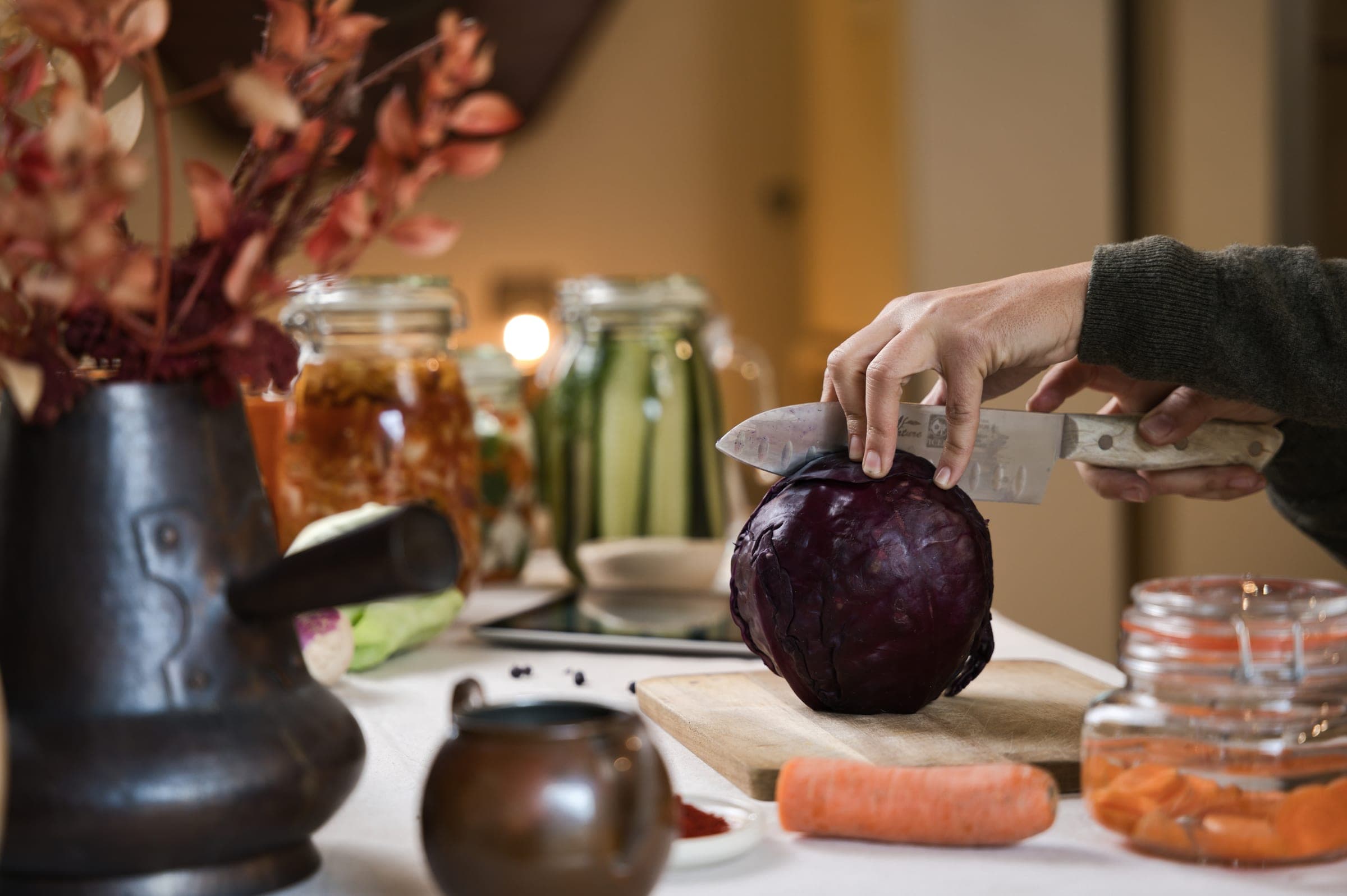 Couve-roxa a ser cortada, com frascos de vegetais fermentados ao fundo